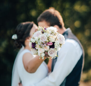 Dos novios se besan con un ramo de flores