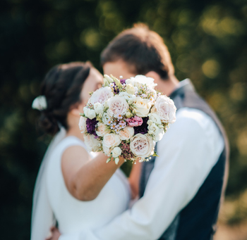 Dos novios se besan con un ramo de flores