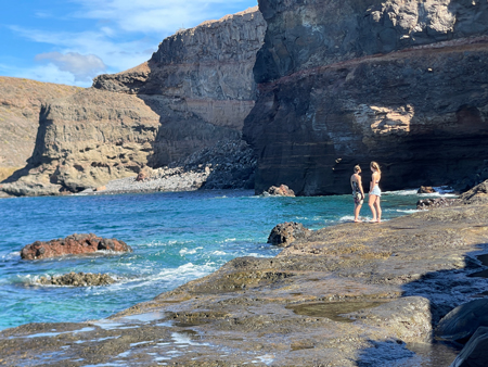 Dos mujeres en la costa de Gran Canaria, simbolizando una boda espiritual rodeada de naturaleza y energía en un entorno único.