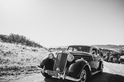 Coche de boda adornado con flores y decoraciones, con los novios recorriendo un paisaje natural durante su ceremonia al aire libre.