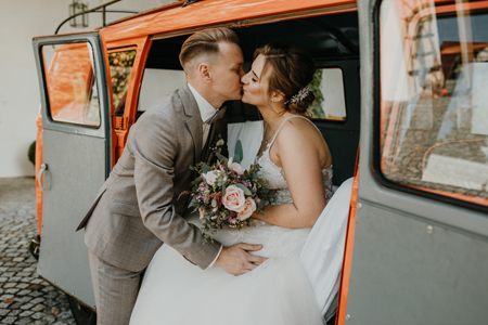 Glückliches Hochzeitspaar küsst sich im Auto und genießt den besonderen Moment nach der Trauung in Zweisamkeit.