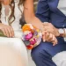 Pareja de novios sentada sosteniendo el ramo y dandose la mano